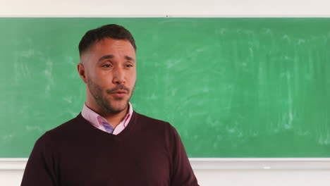 close up shot of mature male teacher in classroom standing in front of board teaching lesson