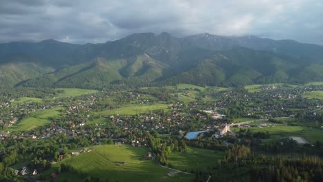 Valley-view-from-Gubałówka---landscape-flyover-of-snowcapped-Polish-Tatry-Mountains,-farmland,-forests,-and-legendary-Giewont-peak-near-Zakopane,-Poland---4K-30FPS-Smooth-Tracking-Forward-3