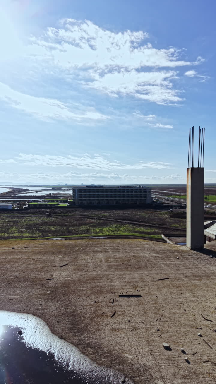 Expansive view of a developing landscape under clear blue skies with distant buildings and green fields