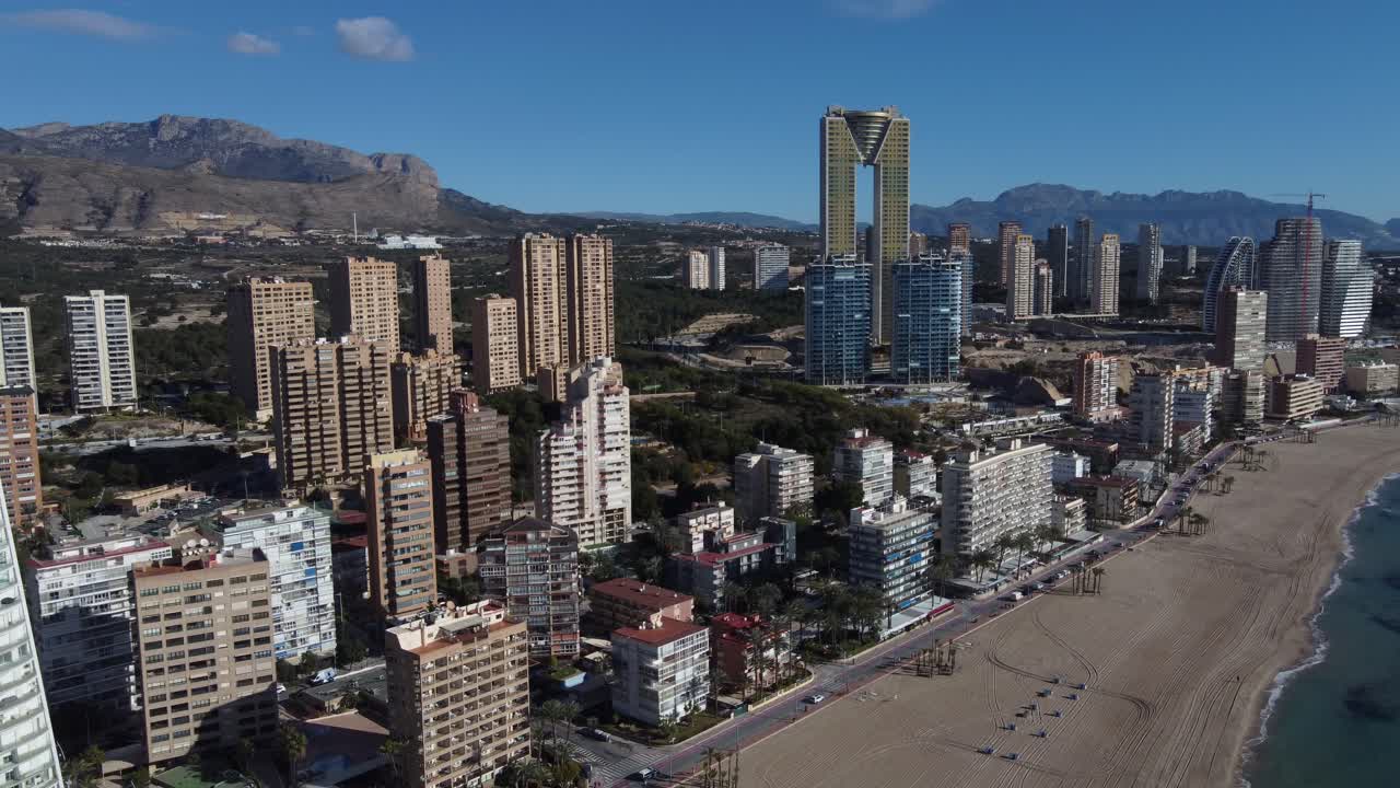 vuelo circular de drones muestra el paisaje urbano de benidorm en el mar mediterráneo con sus rascacielos y la montaña puig campana