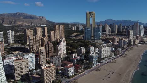 circular drone flight shows the cityscape of benidorm on the mediterranean sea with its skyscrapers and the puig campana mountain