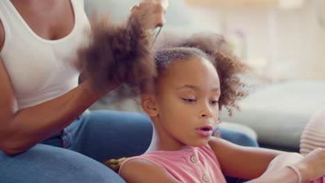 Close-up-of-cute-Black-girl-having-her-pigtails-done-by-her-mum-at-home