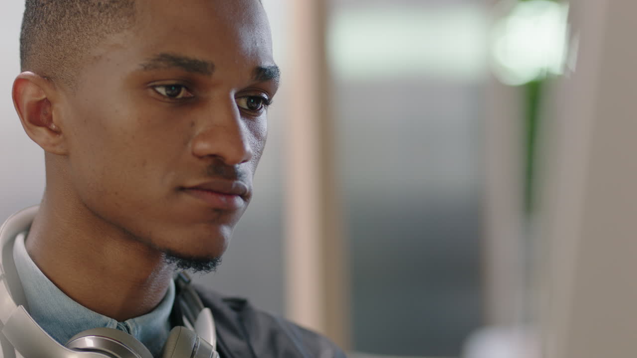 close up portrait young african american businessman using computer brainstorming browsing online research ideas for startup company project networking reading email in office workplace