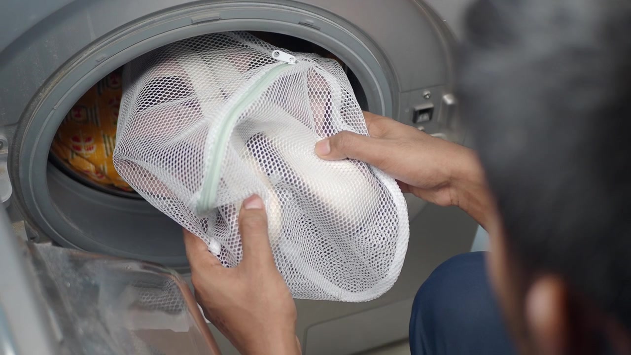 Person Placing Laundry Bag into Washing Machine