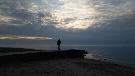 Zeitlupensilhouette-Eines-Mannes,-Der-Bei-Sonnenuntergang-Am-Fleetwood-Beach-In-Lancashire,-Großbritannien,-Zum-Ende-Eines-Stegs-Geht