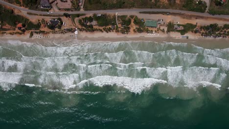 los drones se deslizan a la izquierda revelando una playa con resorts, coches, sombrillas de playa y personas disfrutando del agua, porlamar, isla margarita, venezuela