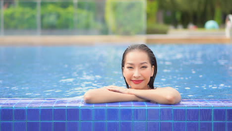 Porträt-Einer-Schönen-Asiatischen-Frau-Im-Pool,-Während-Sie-In-Die-Kamera-Schaut