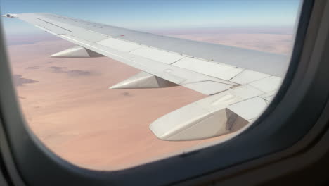 Wide shot of the wing of a large aeroplane in flight shot through the plane window