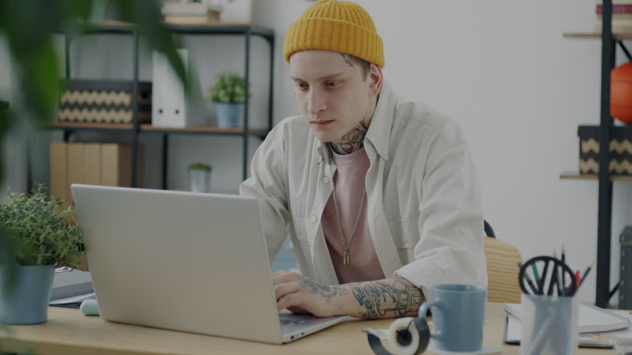 молодой человек работает на ноутбуке в домашнем офисе