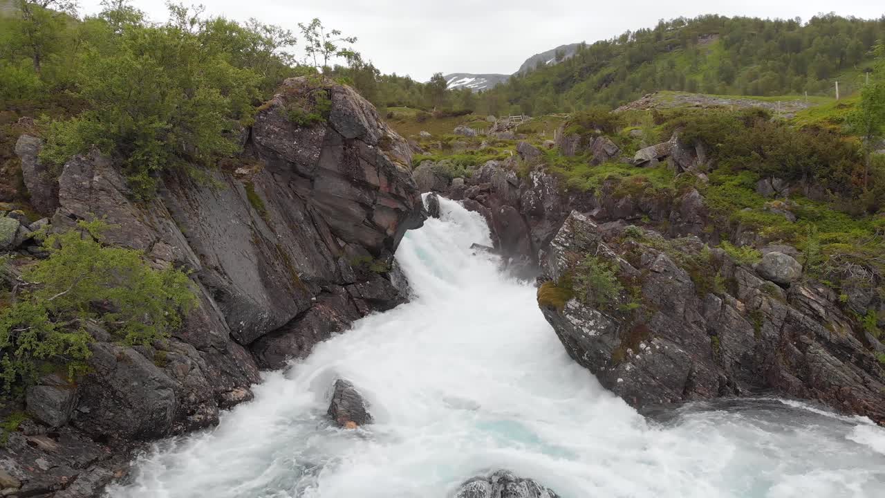 aérea: río cayendo en cascada por rocas rocosas de la ladera de la montaña