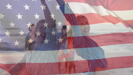 animation of flag of usa over happy caucasian female friends dancing on beach in summer