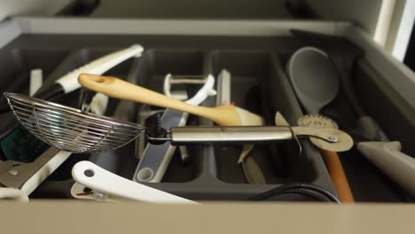 cerca de un cajón de la cocina desordenado lleno de utensilios y aparatos