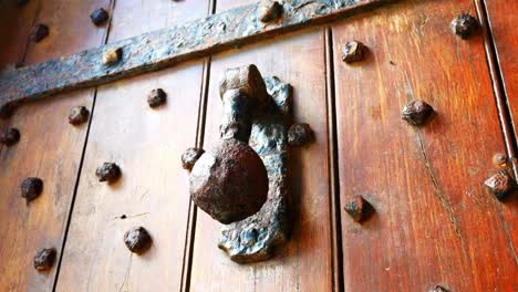 Heavy-wooden-plank-weathered-medieval-door-with-iron-stud-nail-and-door-knocker-handle-ancient-entrance-dolly-left