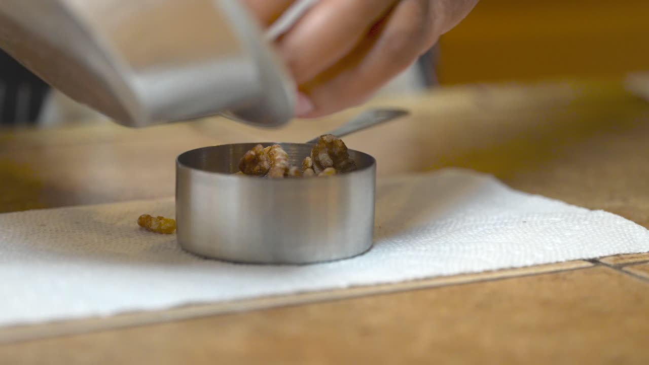 Misurare mezza tazza di noci per preparare un topping crumble per una torta al caffè vegana - isolato