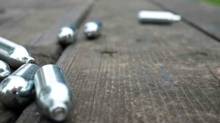 Multiple dropping chrome nitrous oxide laughing gas drug cylinders on wooden bench