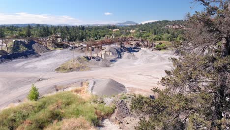 flying from behind a tree to reveal a concrete yard and quarry in a forested countryside