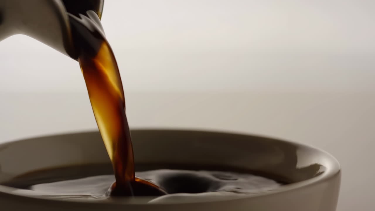 Varm kaffe hældes ned i en hvid kop