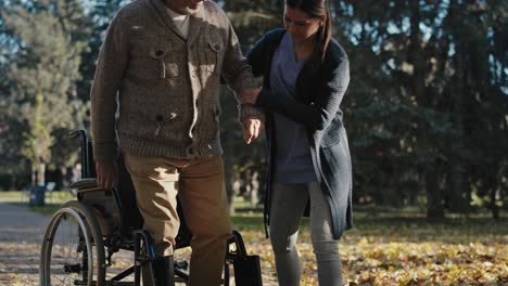 Female-nurse-helping-disability-man-helps-to-get-up-of-the-wheelchair