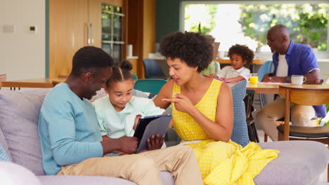 multi-generation family with parents using digital tablet with girl and grandparents help grandson