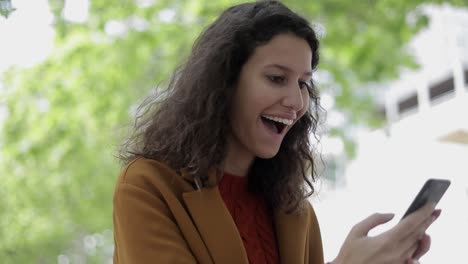 Excited-woman-using-mobile-phone-outdoor