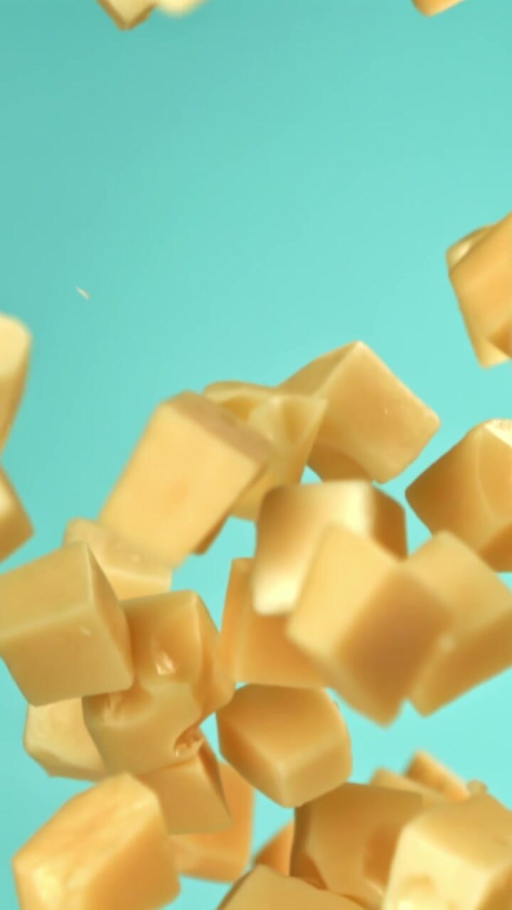 Delicious Cheese Cubes Falling in Slow Motion on a Turquoise Background
