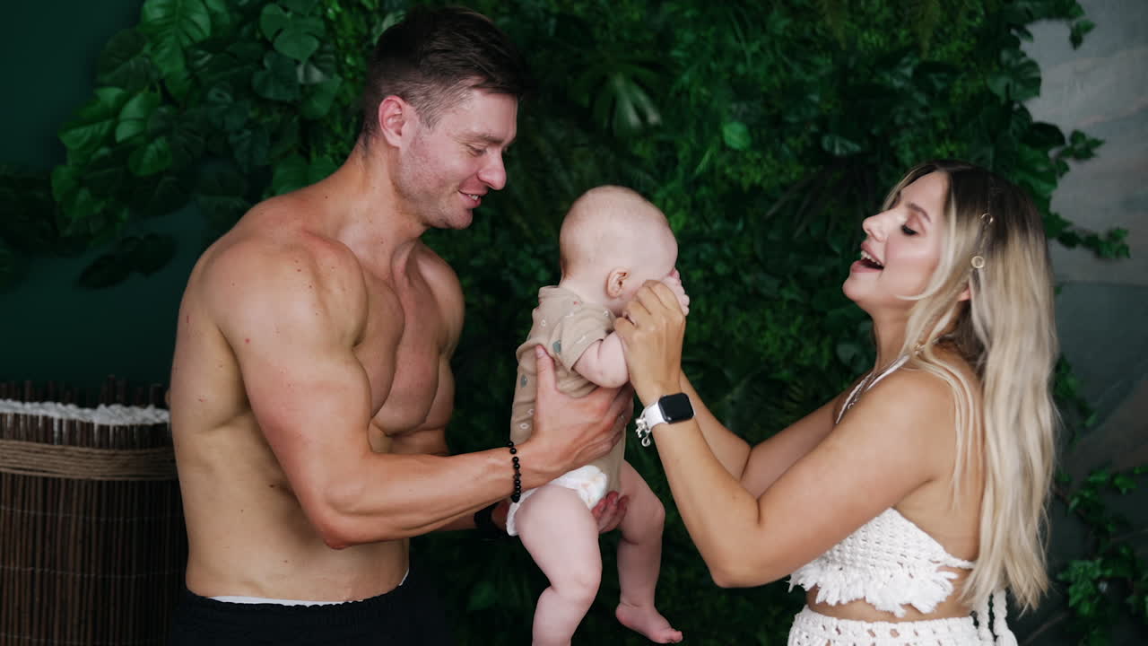 Happy Caucasian family on vacation. Parents hold their little baby boy and dancing with a kid.