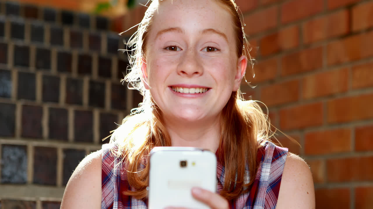 Happy schoolgirl using mobile phone