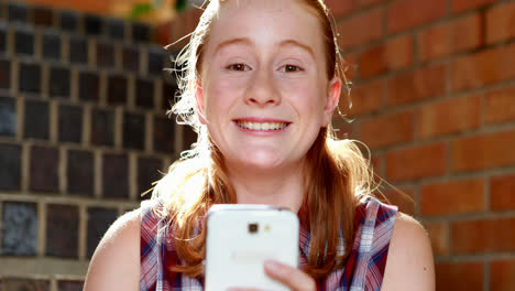 happy schoolgirl using mobile phone