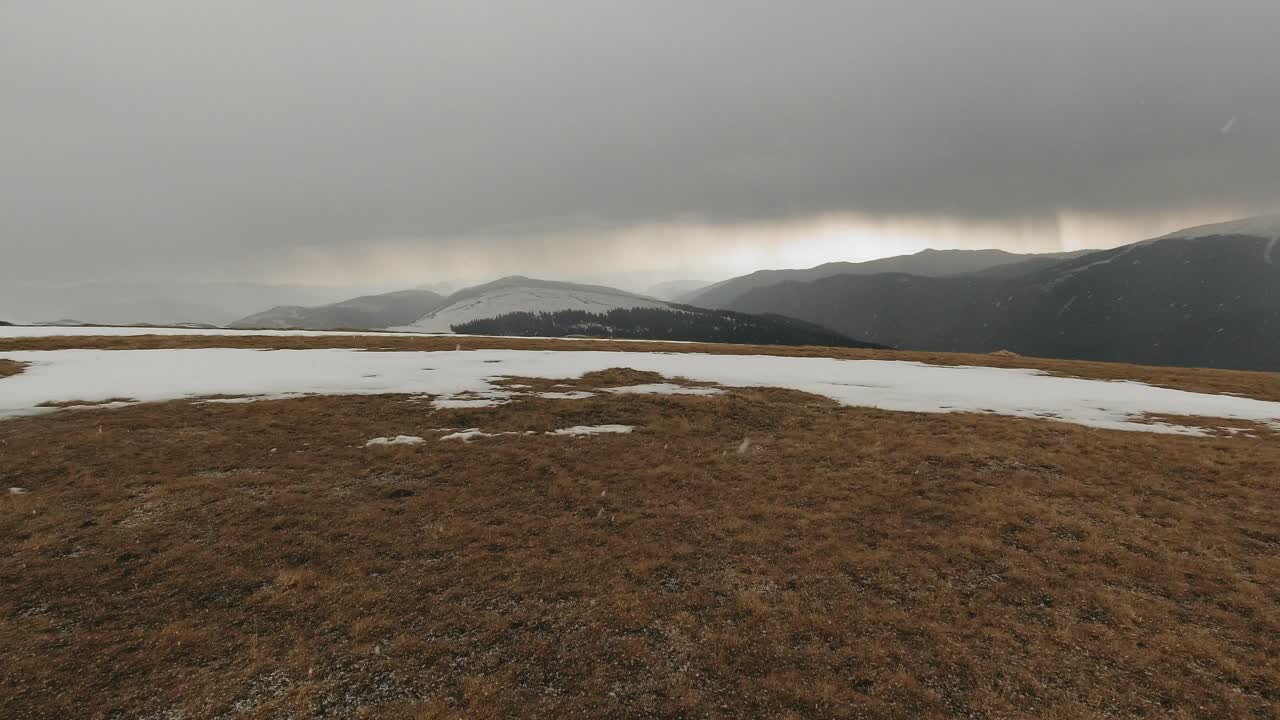 Carrellata grandangolare a destra di un paesaggio montano con nebbia e neve.