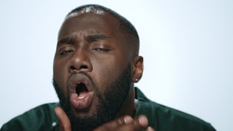 portrait of handsome african american man checking beard in light background.