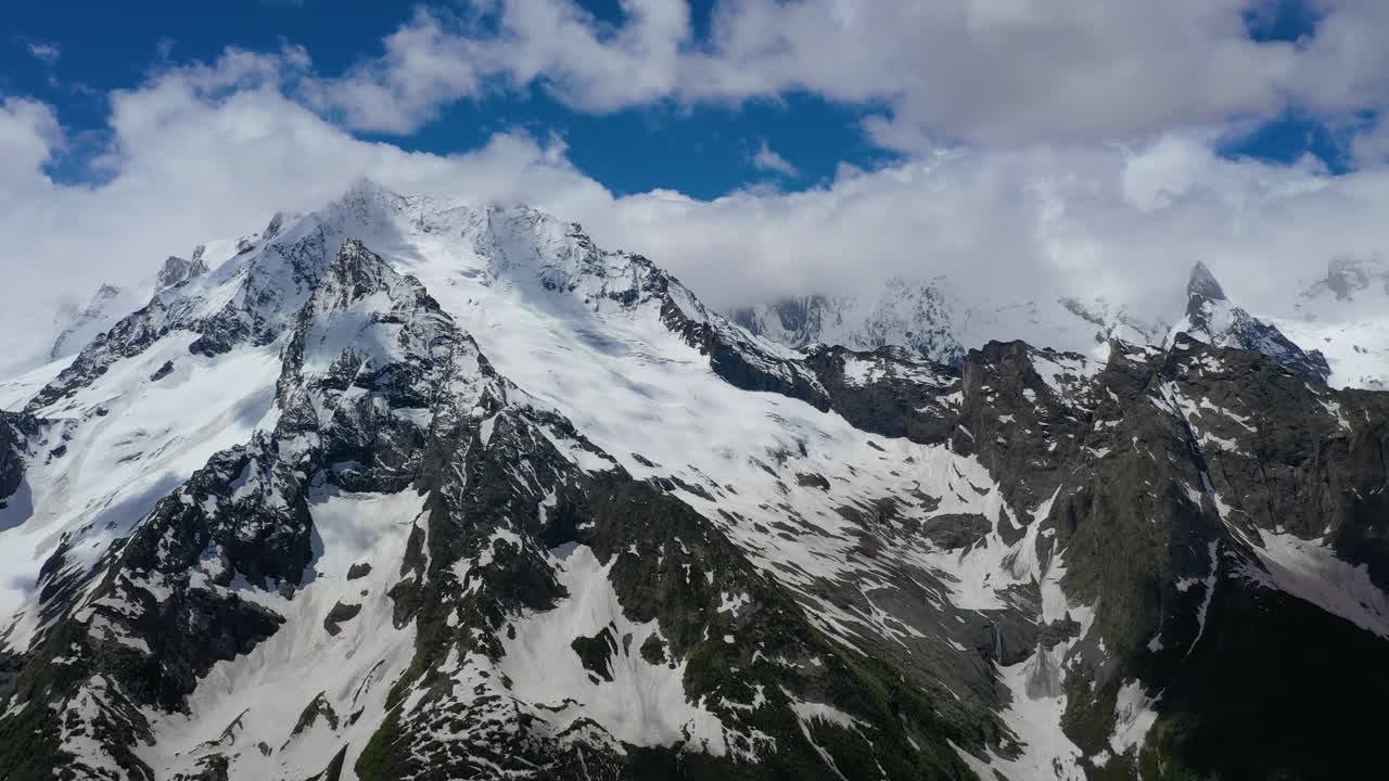 눈 덮인 아름다운 산봉우리와 빙하 위로 산 구름을 통과하는 항공 비행.