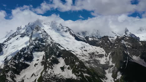 vuelo aéreo a través de nubes montañosas sobre hermosos picos nevados de montañas y glaciares.