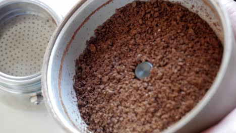grinding fresh coffee beans, close-up of a spoonful of coffee grounds being scooped out