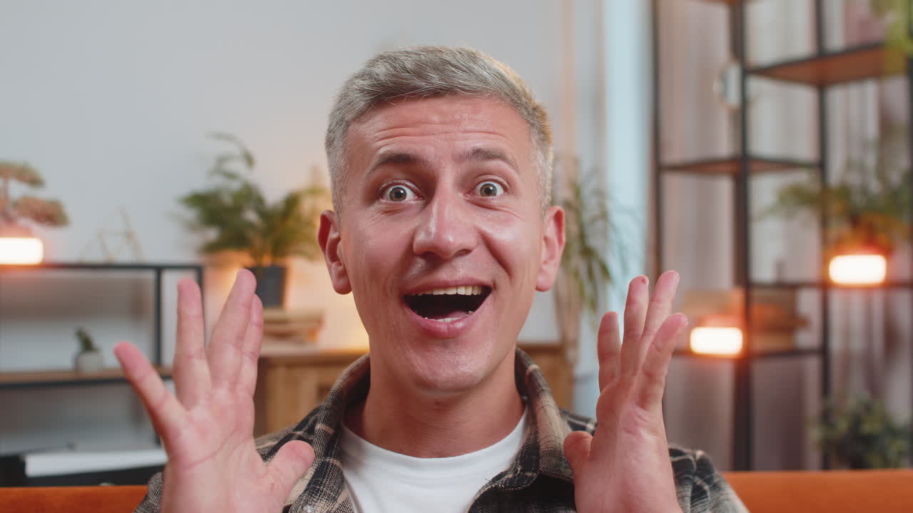 커다란 눈으로 카메라를 쳐다보는 남자가 놀라서 승리에 충격을 받았습니다. 좋은 소식, 승리를 축하합니다.