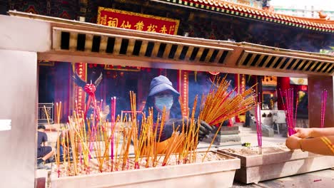 people lighting incense sticks at temple