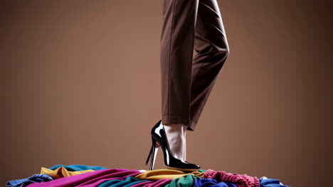 close-up of person in high heels standing on a pile of colorful fabrics