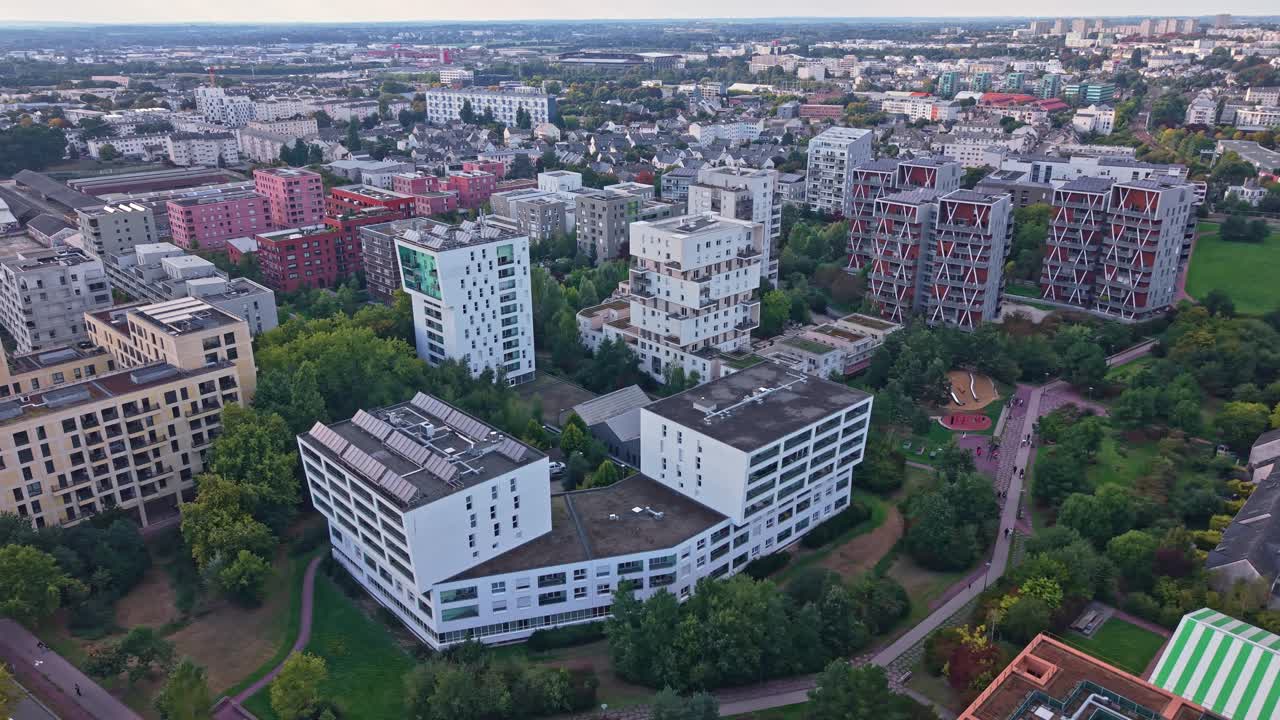 Arc-shaped drone shot revealing La Courrouze towers in Rennes, green areas, and distant cityscape