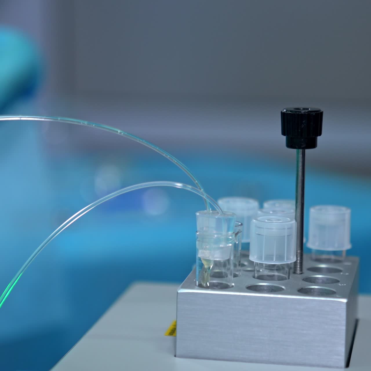 Liquid dripping through the tubes into the test tube. Hand in latex gloves takes the lid off the tube. IVF in modern hospital