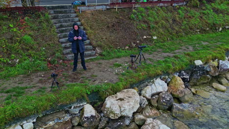 photographer caucasian man by the river fly an aerial drone with remote control