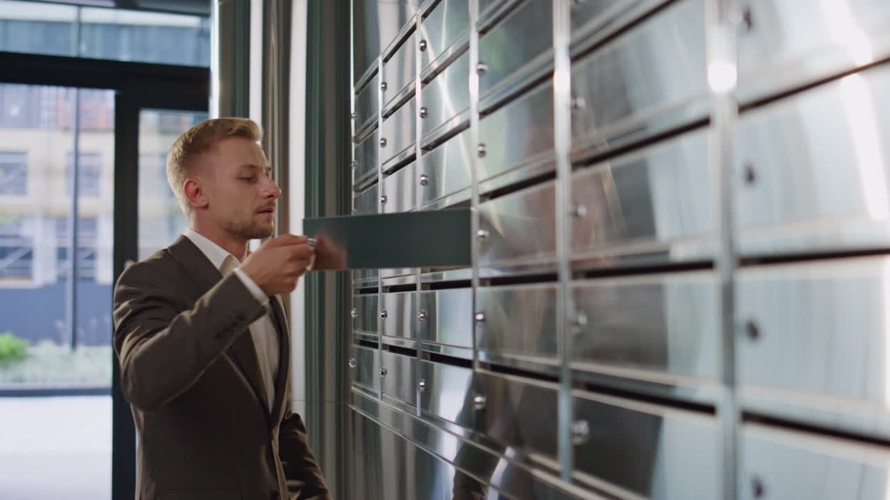 미소 짓는 남자가 복도에서 편지를 확인합니다. 멋진 남자가 슈트를 입고 걸어갑니다.