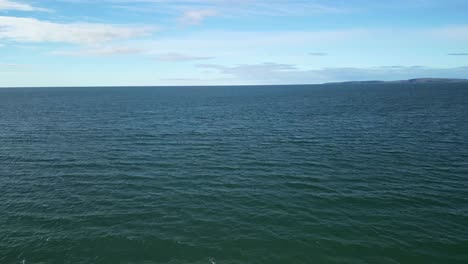 drone flight over sandy beach straight over ocean waves and towards horizon. sunny ireland