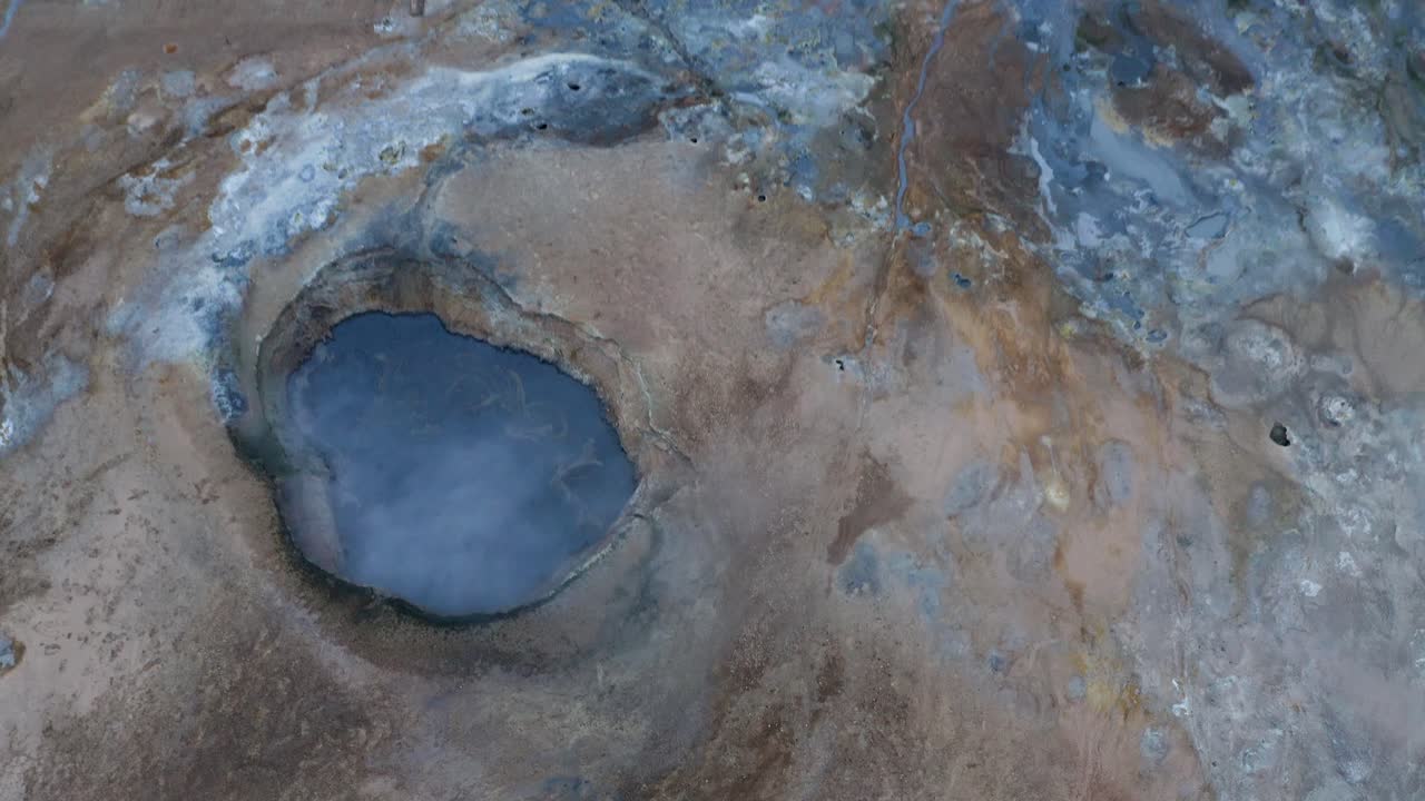Cinematic drone shot of blue colored boiling lake in geological landscape in Iceland - Hverir is a geothermal area