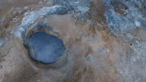 cinematic drone shot of blue colored boiling lake in geological landscape in iceland - hverir is a geothermal area