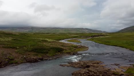 curved river flowing on a flat land in iceland on an overcast day, dolly in