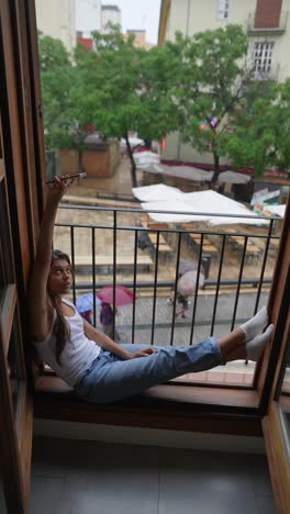 woman on balcony taking a photo during rainy day