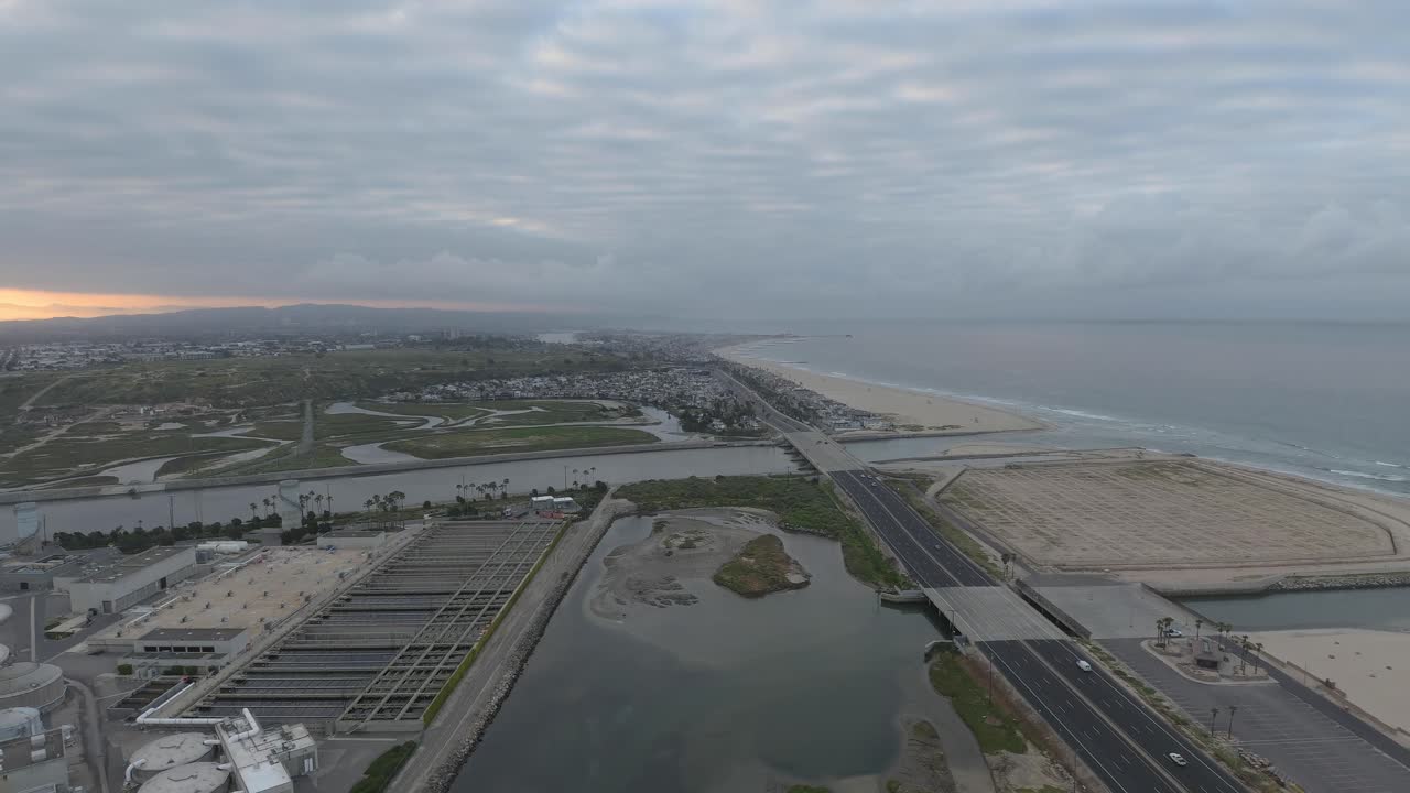 un dron comienza al nivel de las nubes a lo largo de la costa del condado junto a una planta desalinizadora de agua y se desliza lentamente hasta el nivel del mar