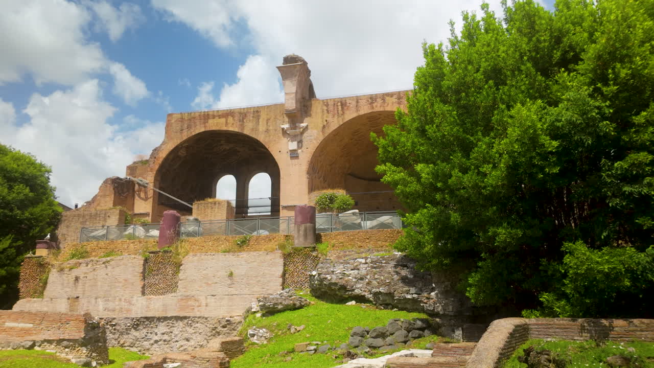 Wider view of Roman ruins with green foliage and stone walls