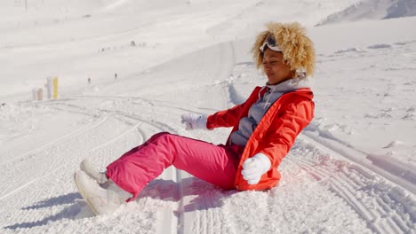 woman in orange snowsuit sitting on ski slope