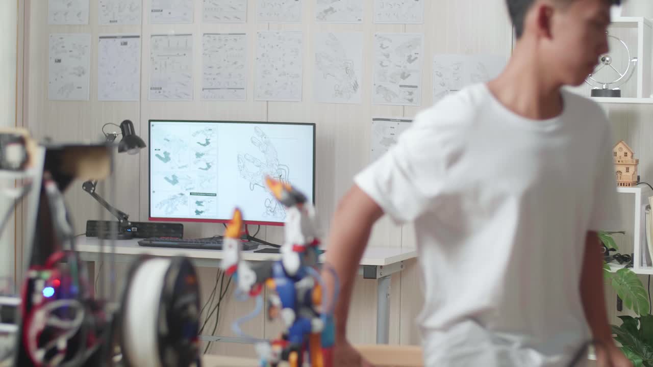 Asian Boy Walking To Look At The Pictures On The Wall While Working About A Cyborg Hand At Home