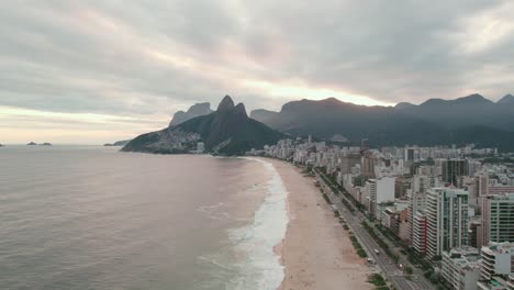 Vista-Aérea-Que-Establece-Las-Playas-De-Ipanema-Y-Leblon-Con-Una-épica-Puesta-De-Sol-Nublada-Con-La-Colina-Dos-Hermanos-Al-Fondo,-Río-De-Janeiro,-Brasil